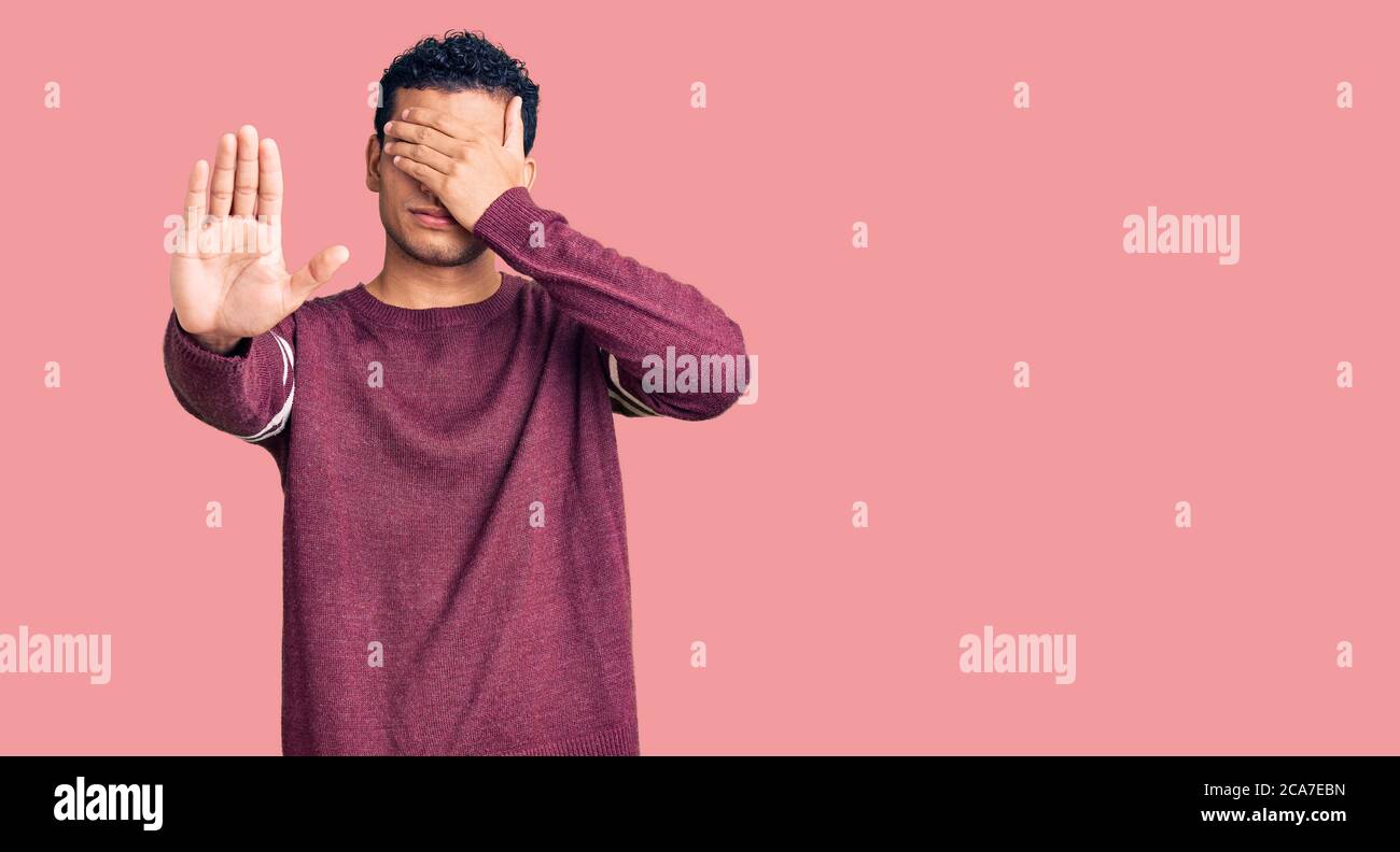 Hispanic handsome young man wearing casual clothes covering eyes with hands and doing stop gesture with sad and fear expression. embarrassed and negat Stock Photo