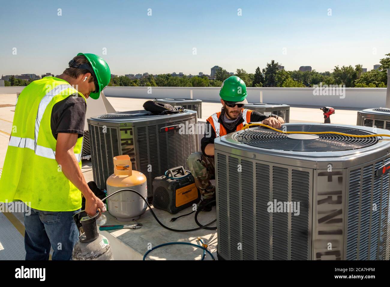 Denver, Colorado - Technicians work on the air conditioning system on the roof of an affordable housing building under construction. Stock Photo