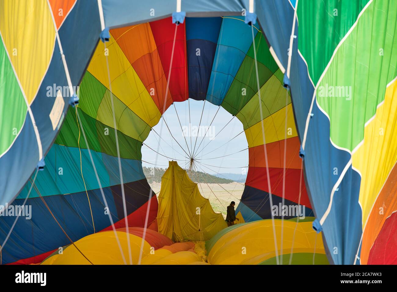 Man standing inside deflating hot air balloon. Showcasing the immense size of the balloon. Stock Photo