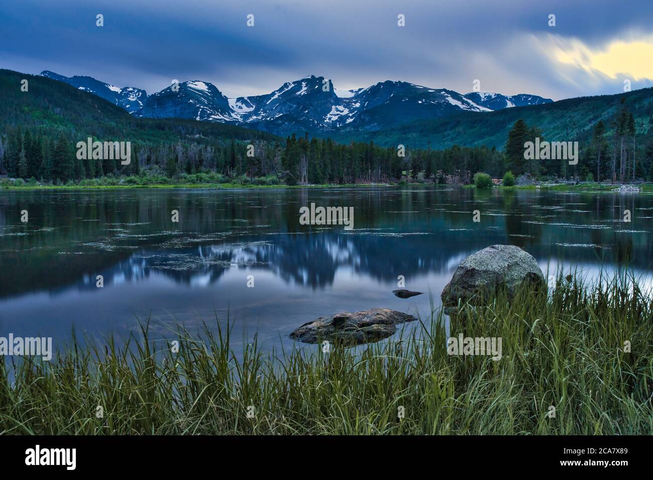 Sunset on Sprague lake in the rocky mountains of colorado. People fly fishing under the shadow of the beautiful mountain range Stock Photo