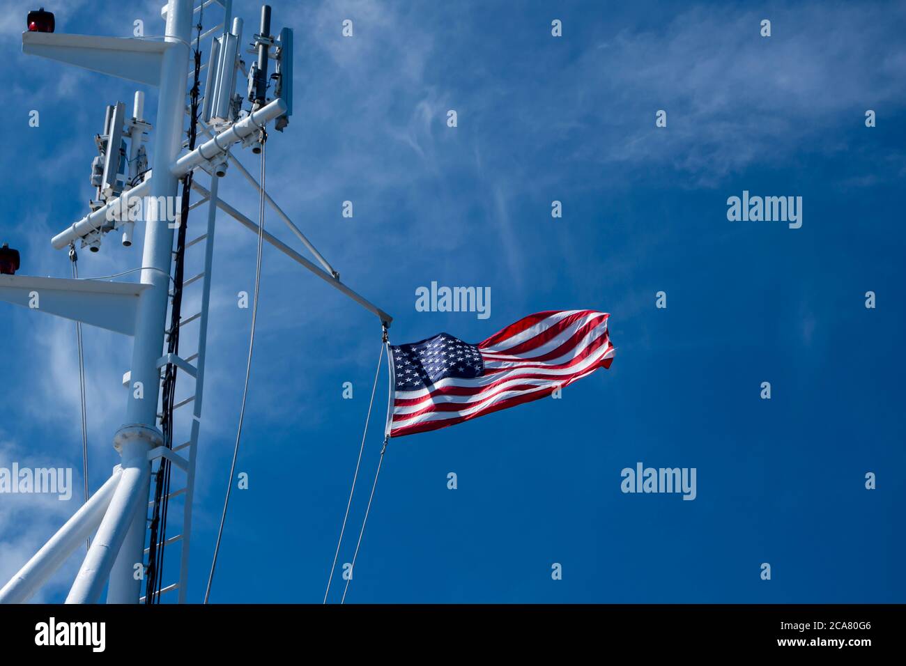 An American ensign blows in the wind as it hangs from a gaff at the stern of a boat Stock Photo