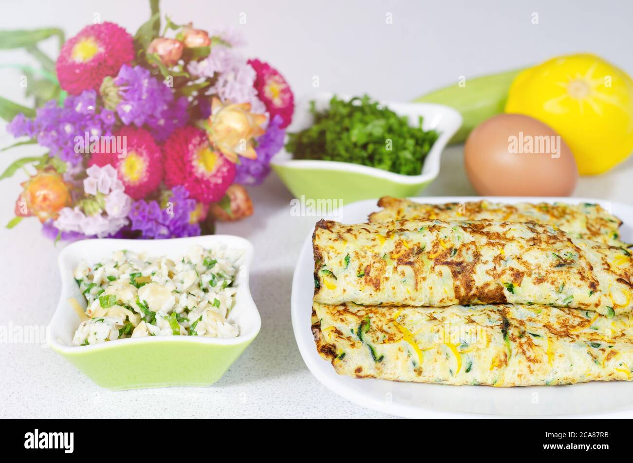 Delicious omelet roll with cheese and zucchini filling on a white table Stock Photo