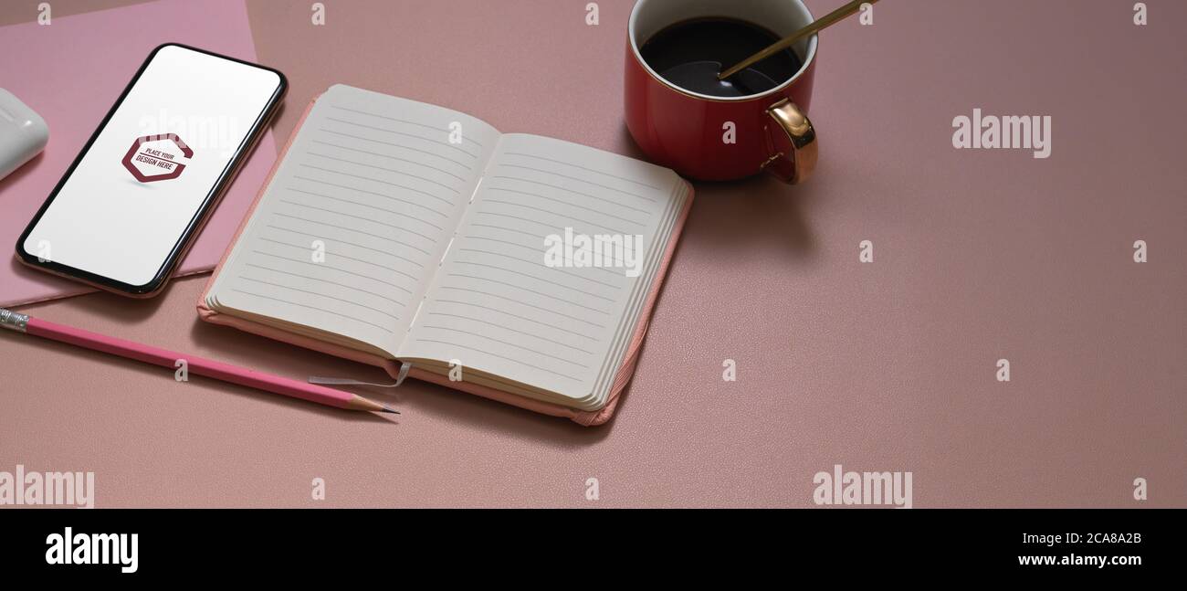 Cropped shot of pink study table with mock up smartphone, opened ...