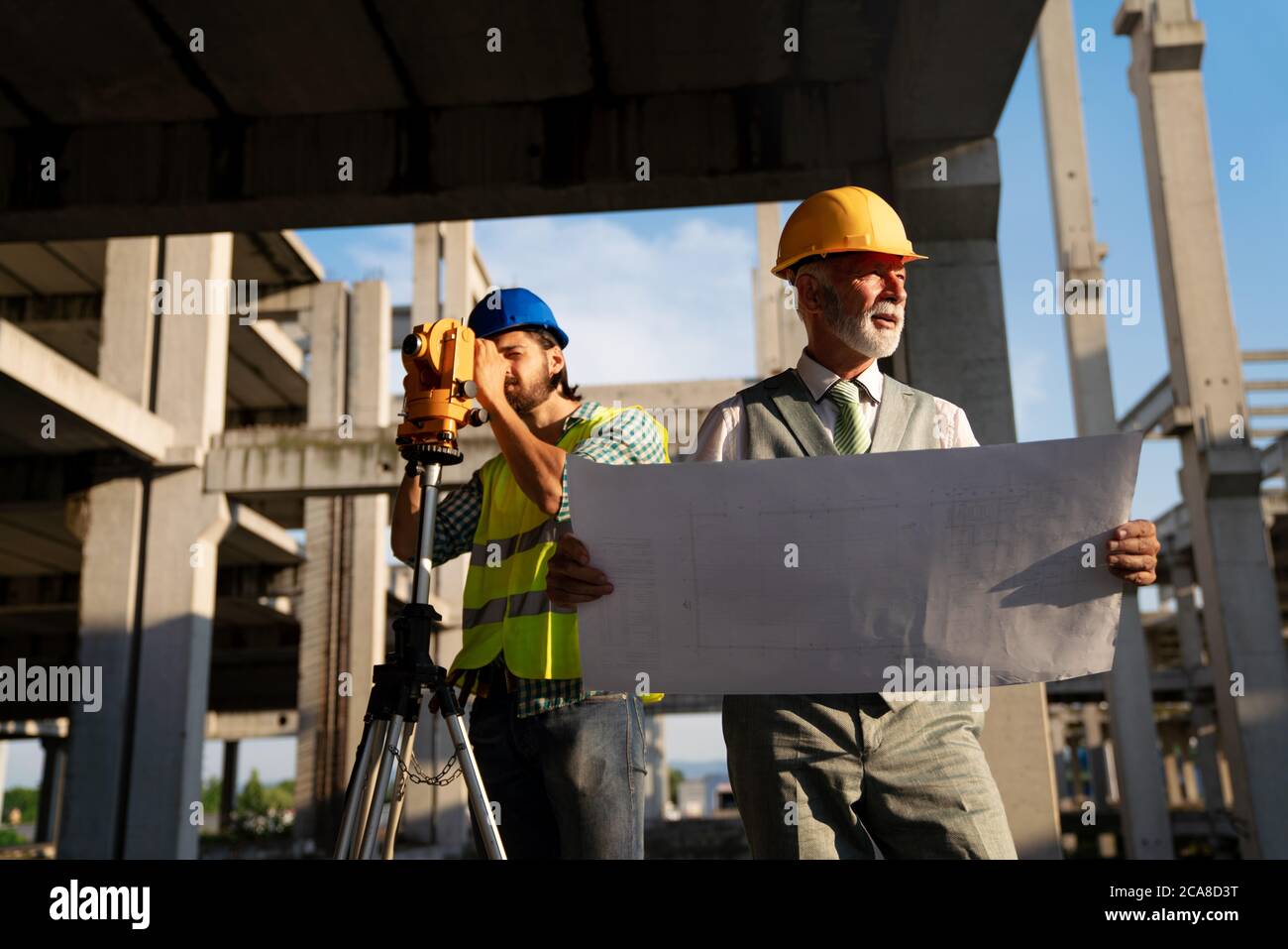 Two satisfied engineers talking at building site with construction structure in background Stock Photo