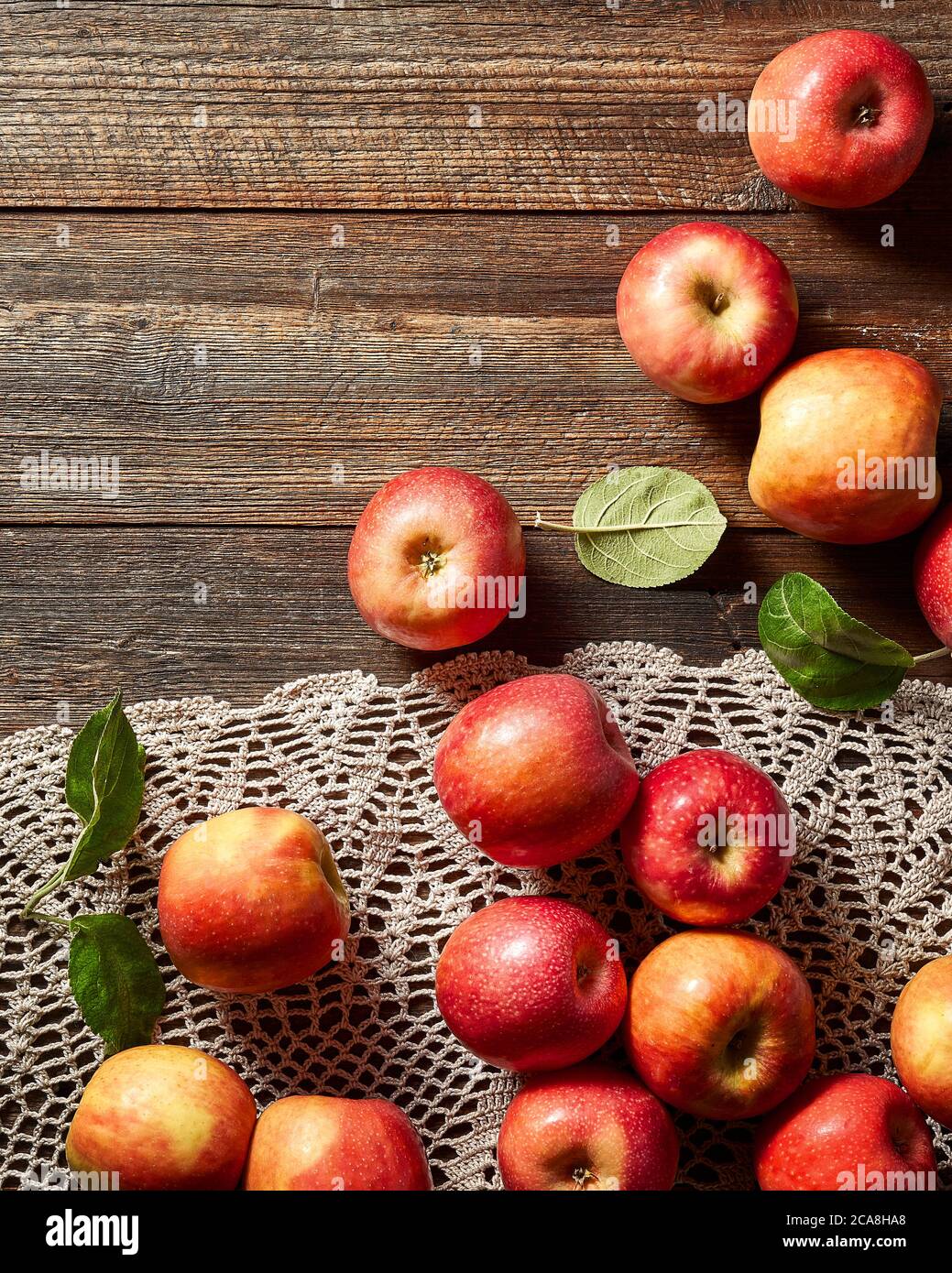 Red apple on rustic wooden table and crochet tablecloth. Summer or autumn season. Stock Photo