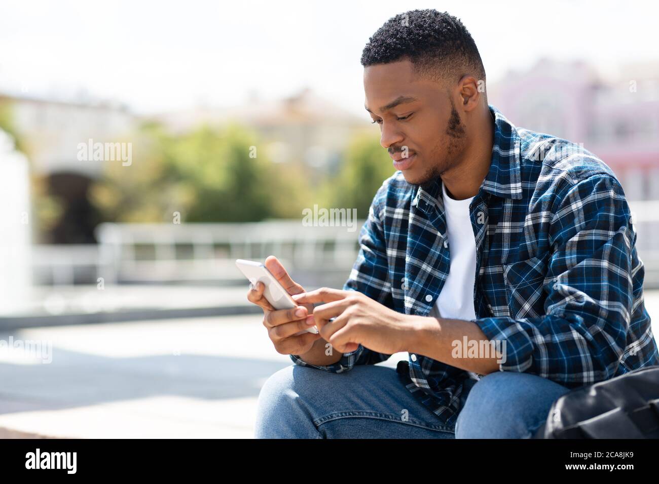 Portrait of black person texting sms on his smart phone Stock Photo