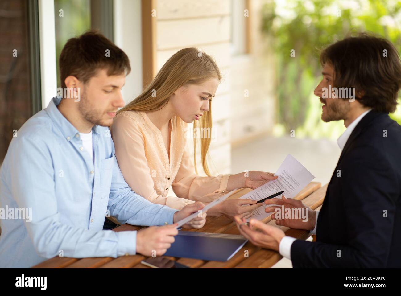 Millennial couple unhappy about property purchase price and realtor near house for sale Stock Photo