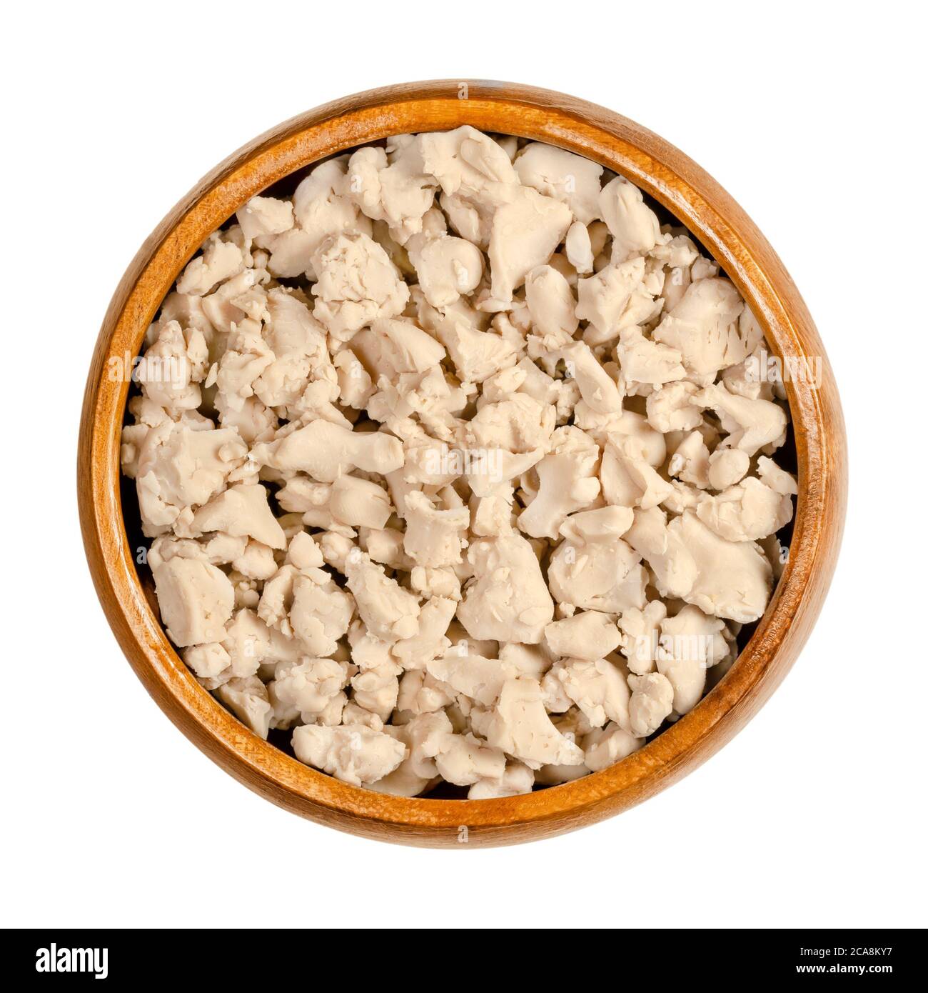 Crumbled fresh bakers yeast in a wooden bowl. Compressed fresh yeast, crushed with fingers, used in baking as a leavening agent. Saccharomyces cerevis Stock Photo