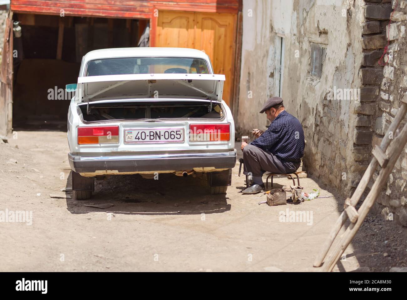 Xinaliq / Azerbaijan - July 8, 2019: Man fixing old Lada Soviet car in village Stock Photo