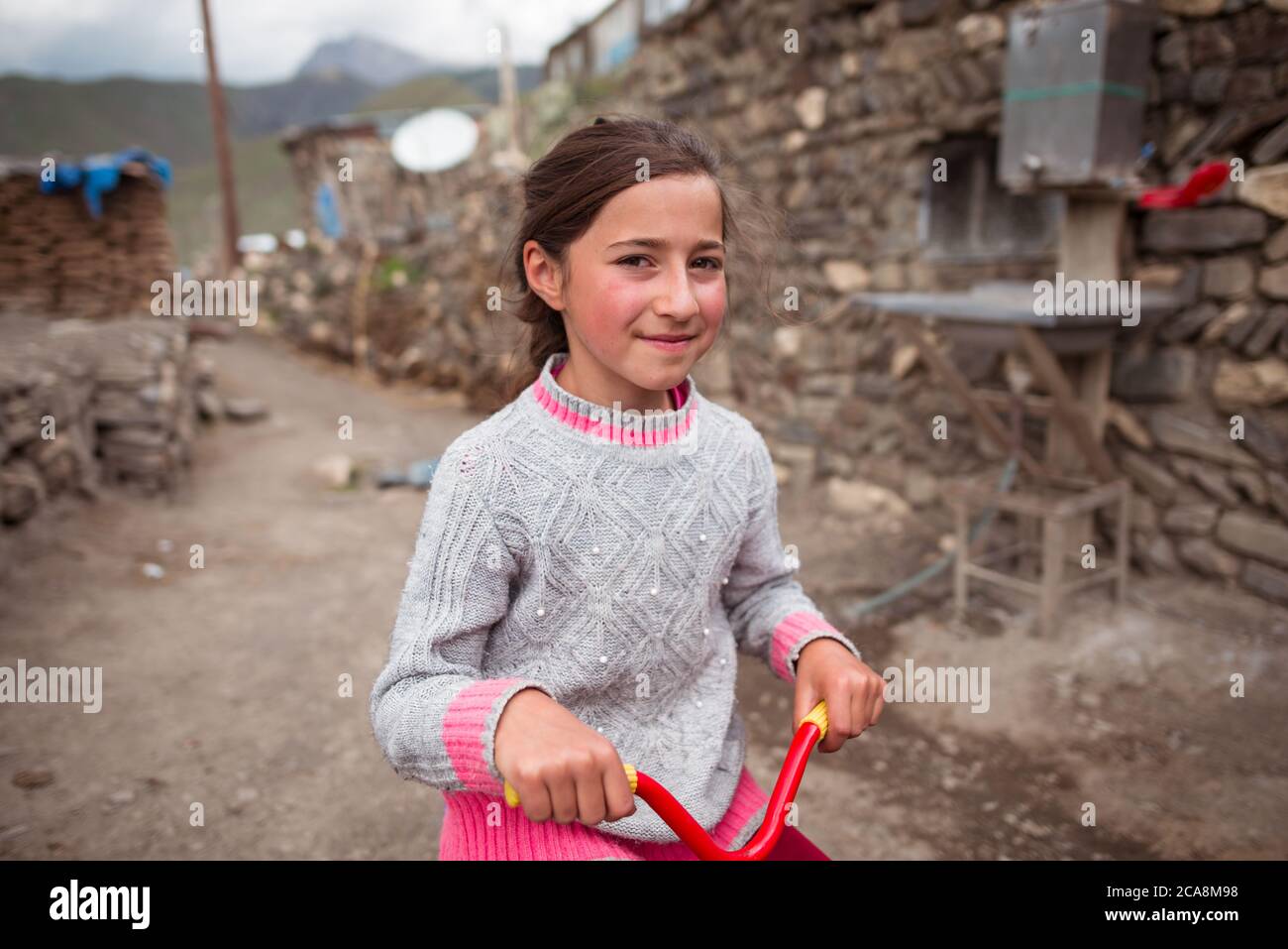 Xinaliq / Azerbaijan - July 8, 2019: Portrait of cute kid riding colorful small bicycle in mountain village Stock Photo