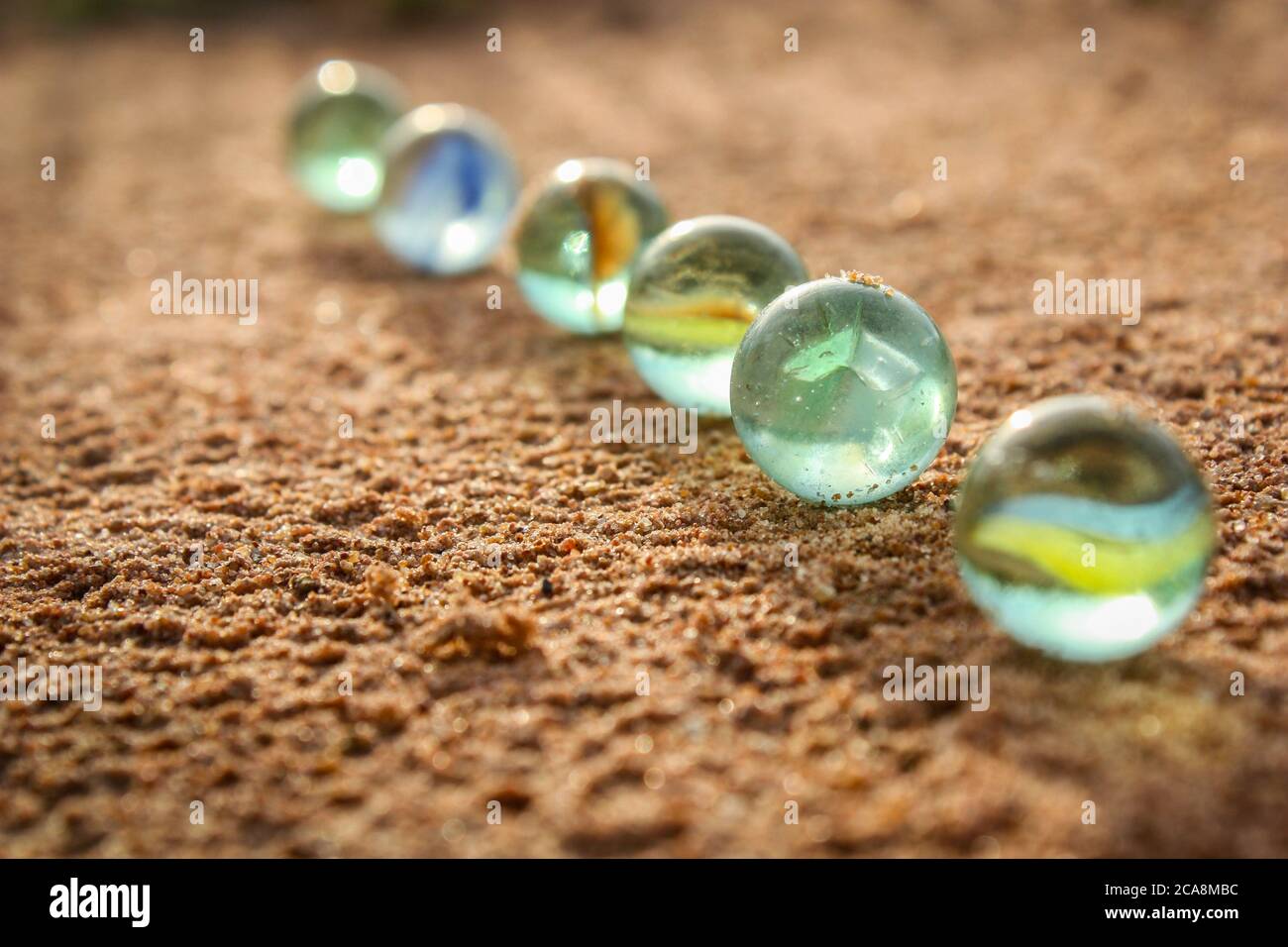 you can see marbles lined up on the sand floor Stock Photo