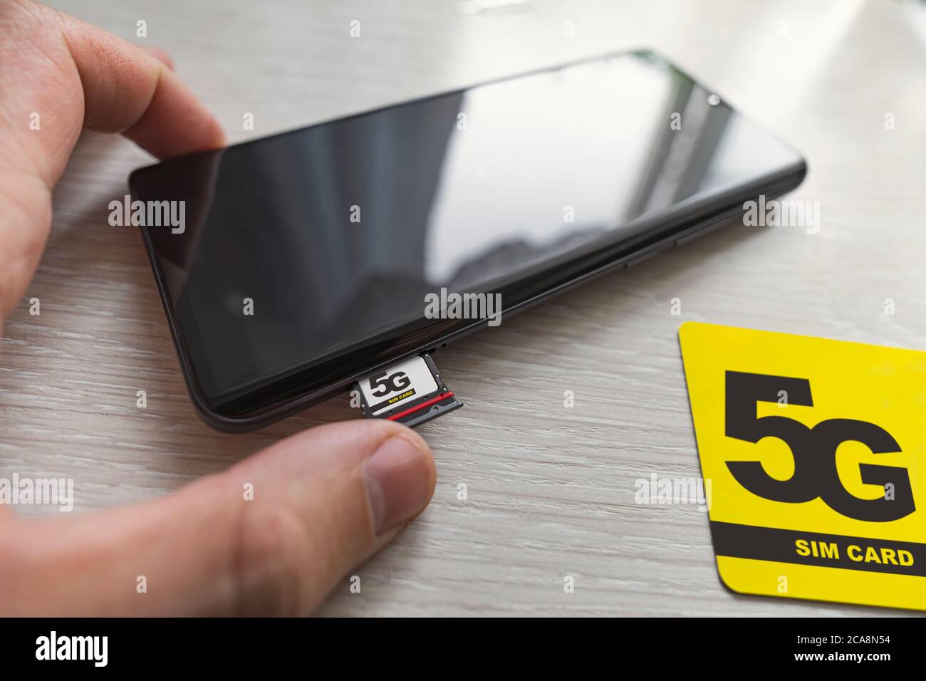 Replacing 4G SIM card with a high speed 5g SIM card close up on the store's wooden table Stock Photo