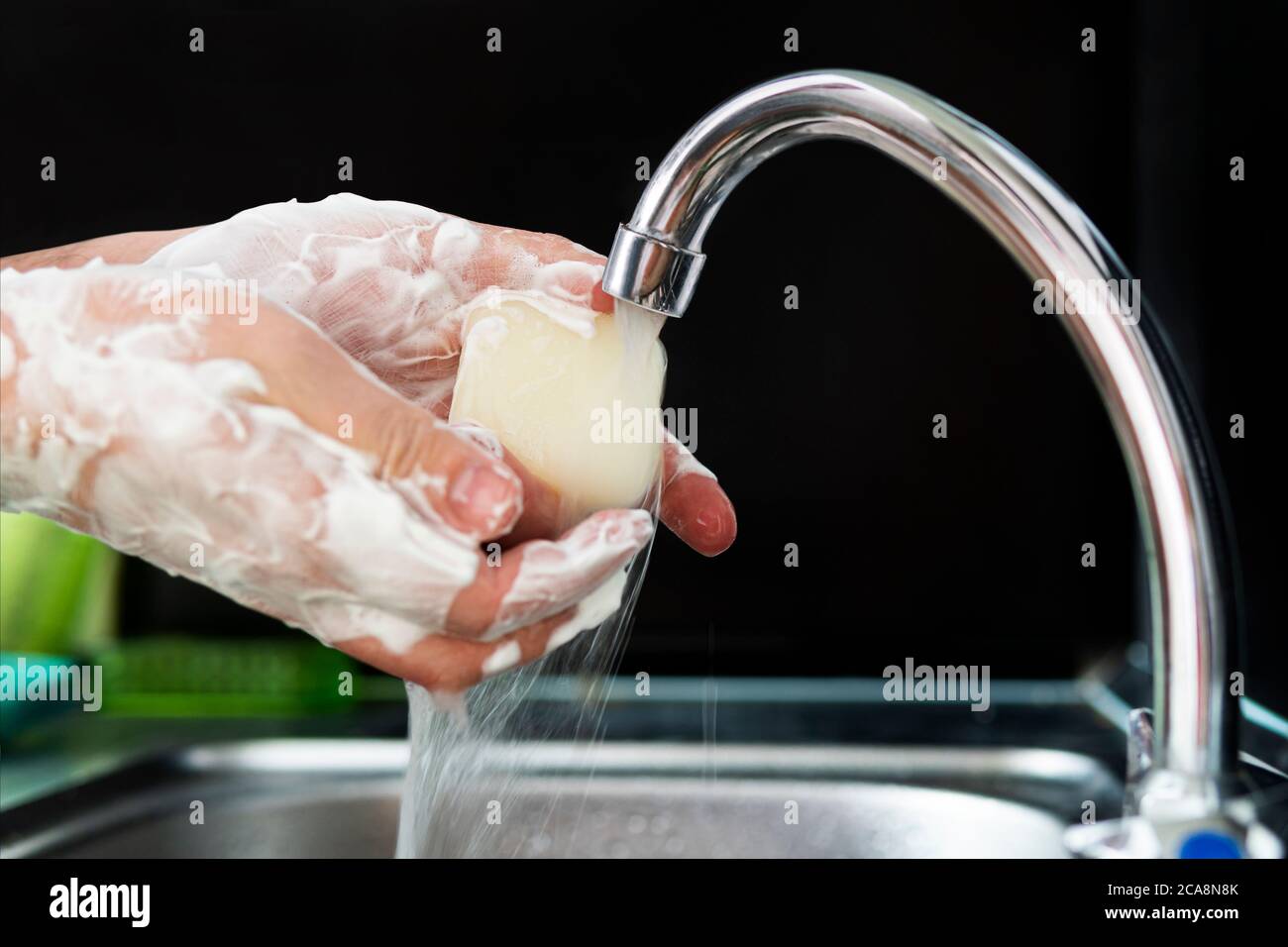 Washing hands rubbing with soap man for winter flu virus prevention, hygiene to stop spreading germs. man washes his hands with soap on black Stock Photo