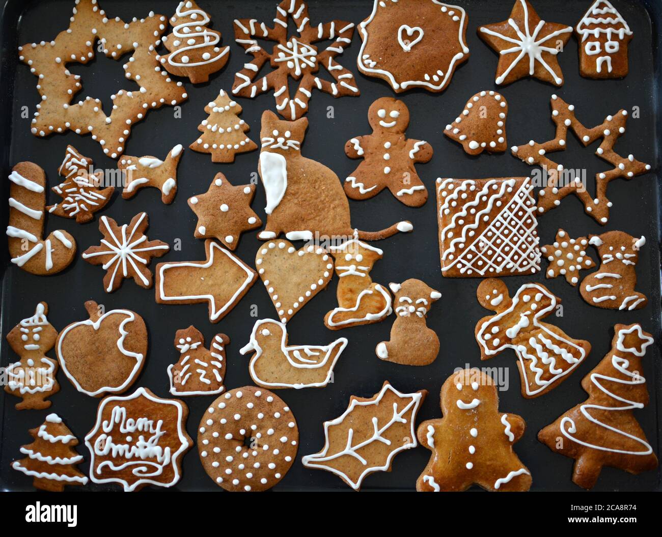 Gingerbread cookies decorated with royal icing on baking sheet. Christmas food. Stock Photo