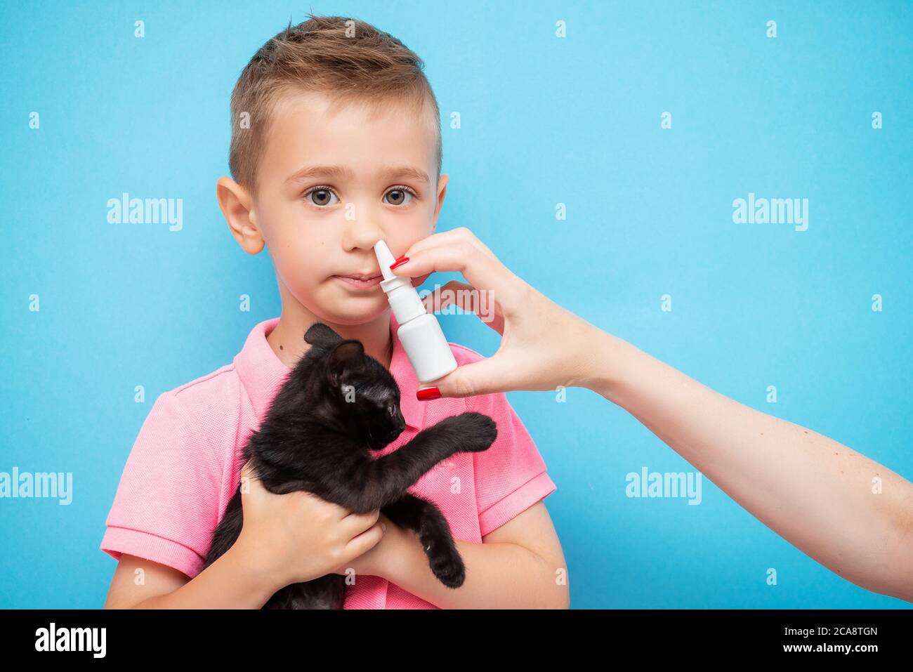 Cute boy with a kitten in his arms and his mother's hand applies a
