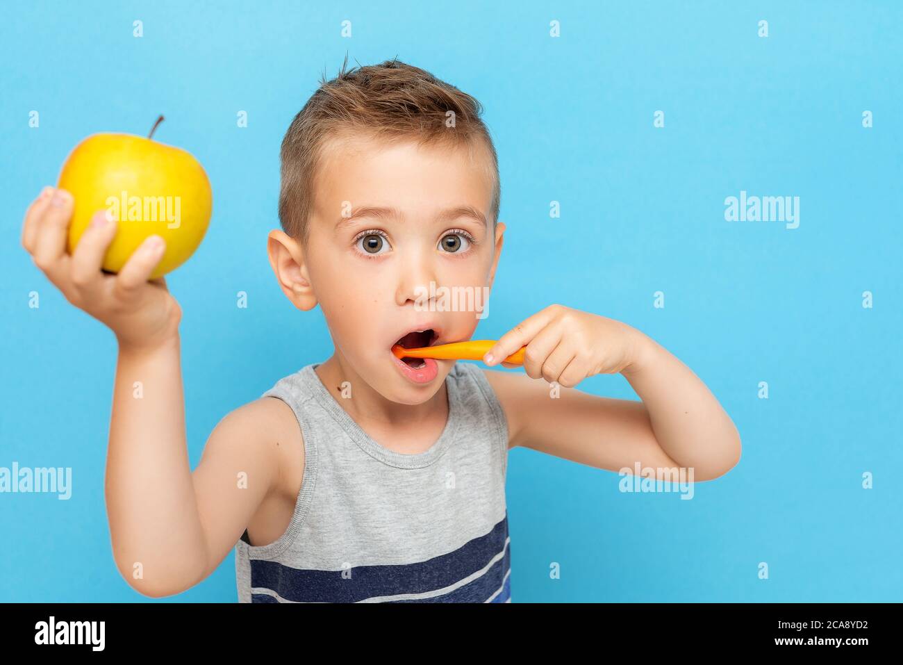 Funny boy brushing teeth with manual toothbrush and holds an apple in his  other hand Stock Photo - Alamy
