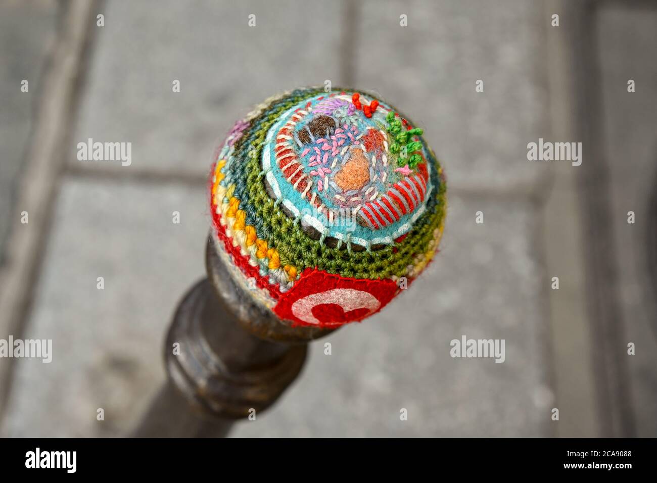 Close-up of the top of a bollard covered with a colorful crochet fabric (yarn bombing) in a street of the Marais district, Paris, France Stock Photo