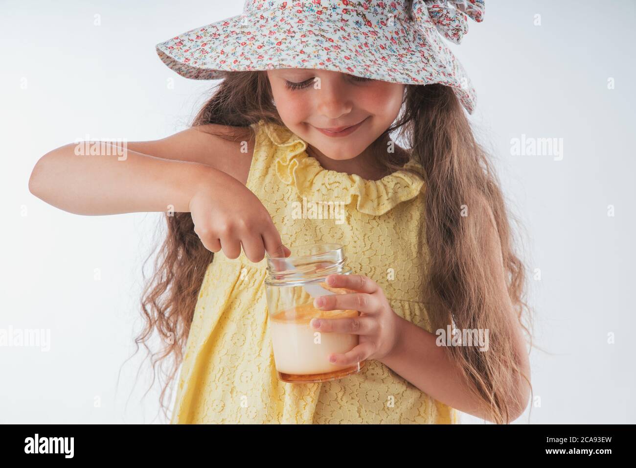 Beautiful little girl eating tasty cream dessert portrait isolated on white background Stock Photo