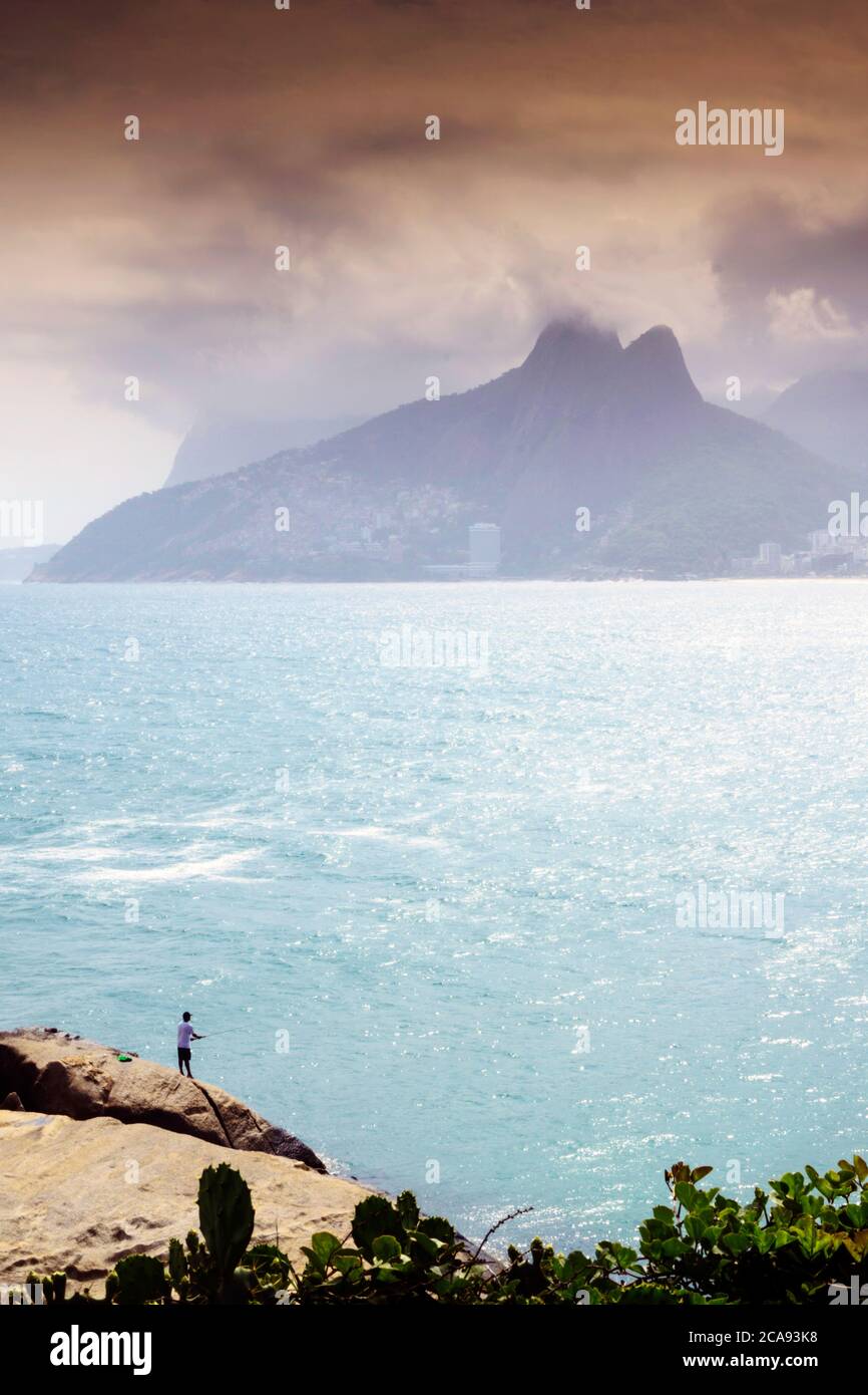 A fisherman on the Arpoador rocks next to Ipanema beach, Rio de Janeiro, Brazil, South America Stock Photo