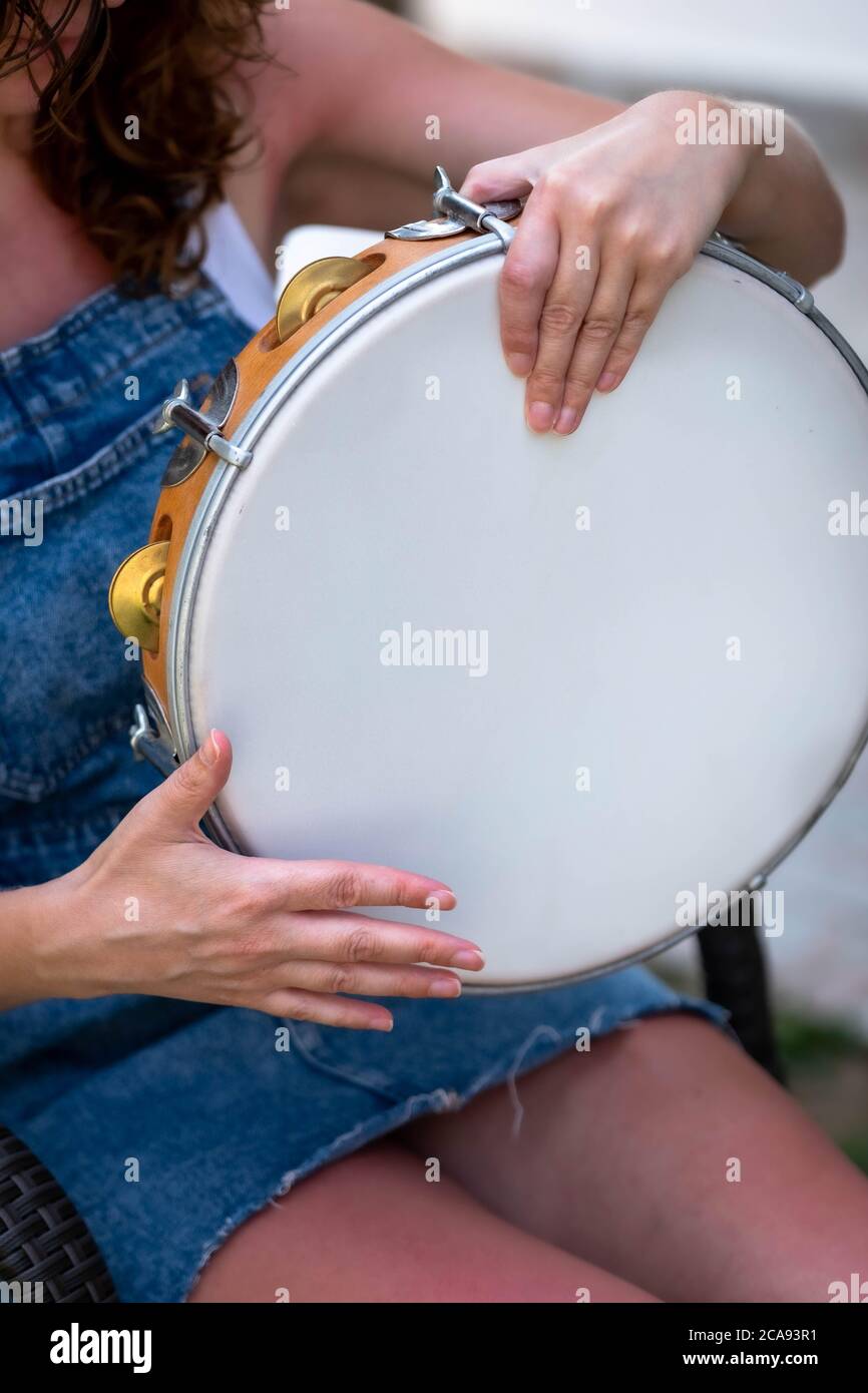 Woman holds in his hand a folk tambourine in greece. Side profile of a Woman playing a tambourine Instrument. Stock Photo