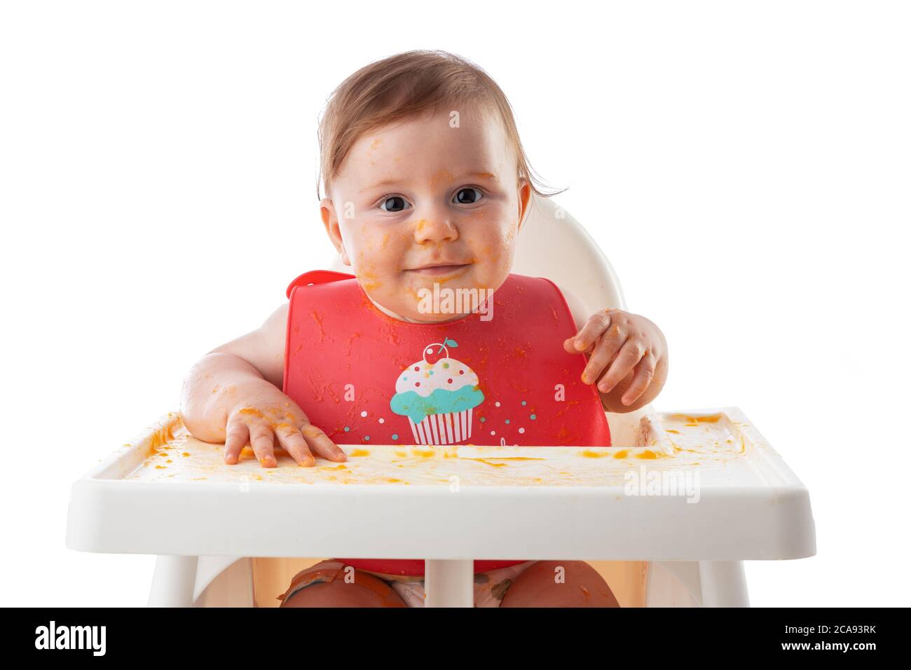 Cheerful baby child eats food itself with hands. Portrait of happy dirty kid boy in high chair and messy  around. Stock Photo