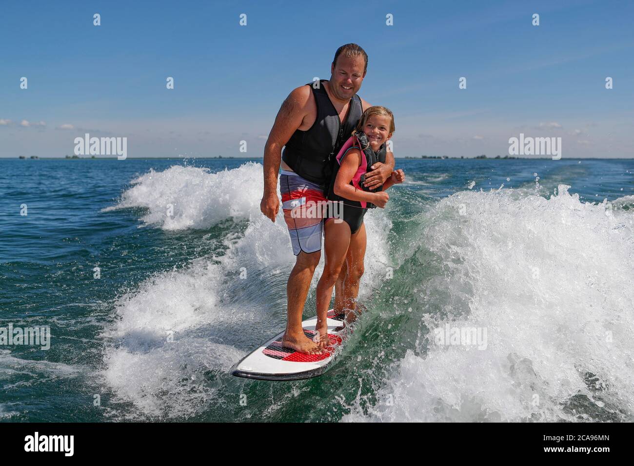 A man and a child together on a surfboard. Stock Photo
