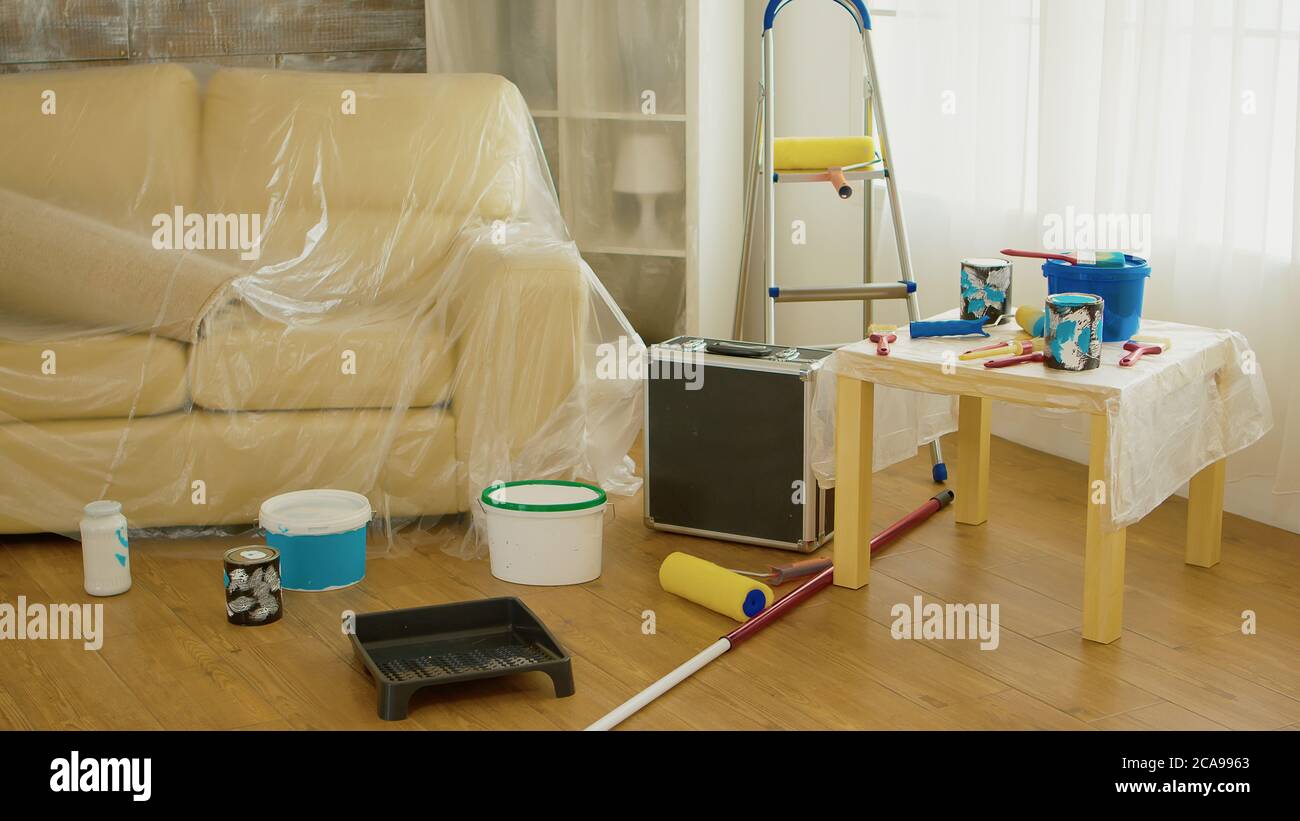 Sofa covered with plastic sheet during home renovation. Home during renovation decoration and painting. Interior apartment improvement maintenance. Roller ladder for house repair Stock Photo Alamy