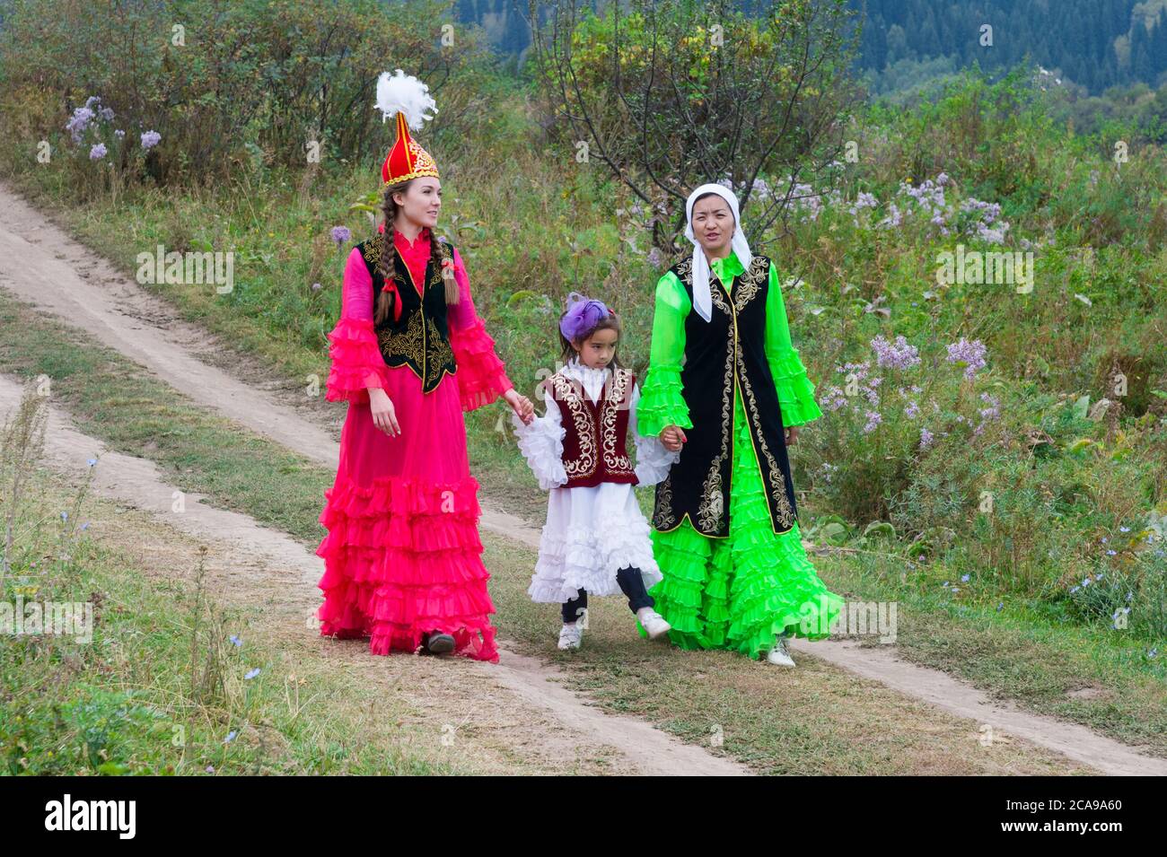 Two Kazakh women walking with a child, Kazakh ethnographical village Aul Gunny, Talgar city, Almaty, Kazakhstan, Central Asia, For editorial Use only Stock Photo