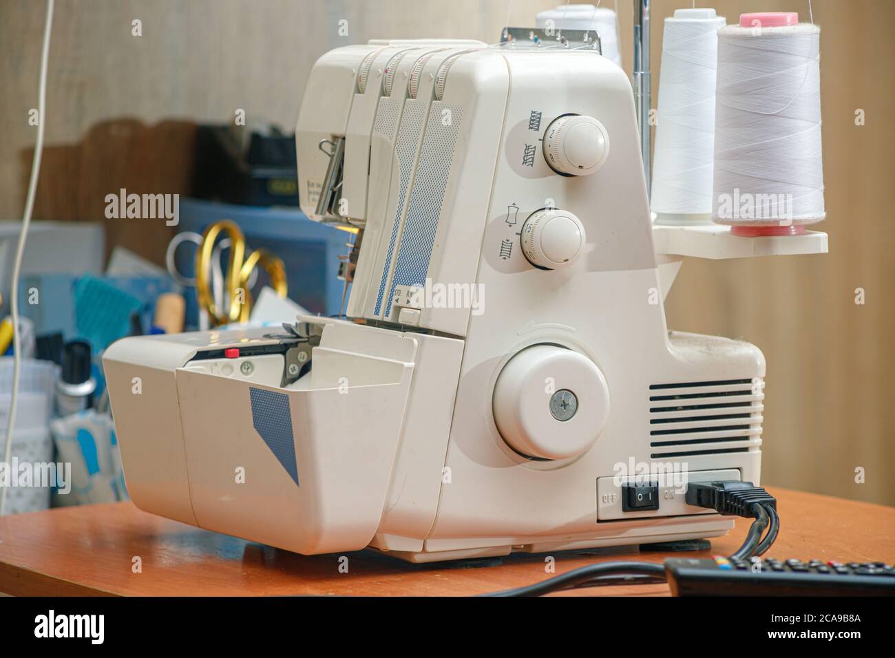 white sewing machine on the table with white threads Stock Photo