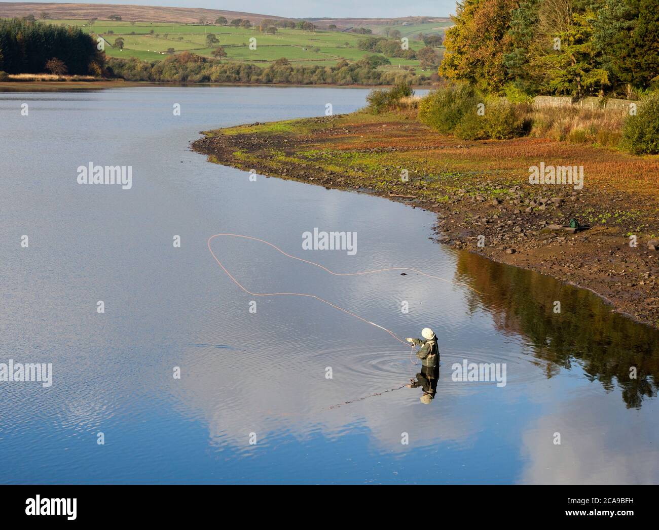 Autumn view of a fly fisherman casting his line at Fewston Reservoir in the Washburn Valley, North Yorkshire Stock Photo