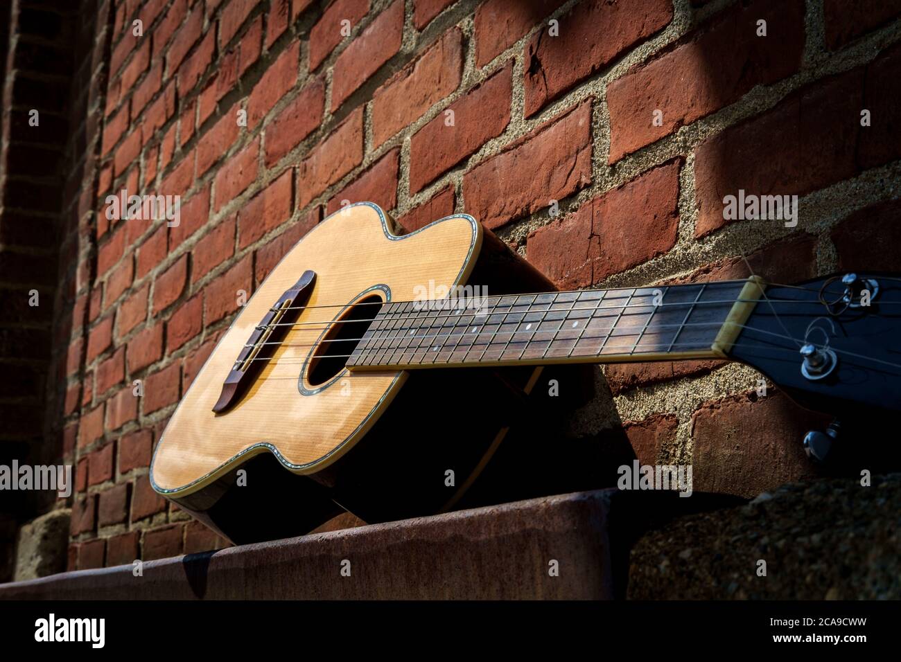 Acoustic baritone ukulele guitar left outside performance venue againts