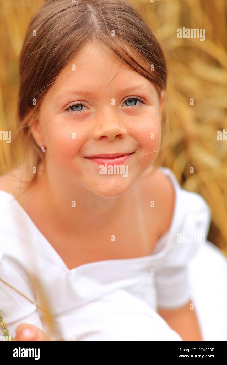 Little girl with a bouquet of wildflowers in her hands in a wheat field ...