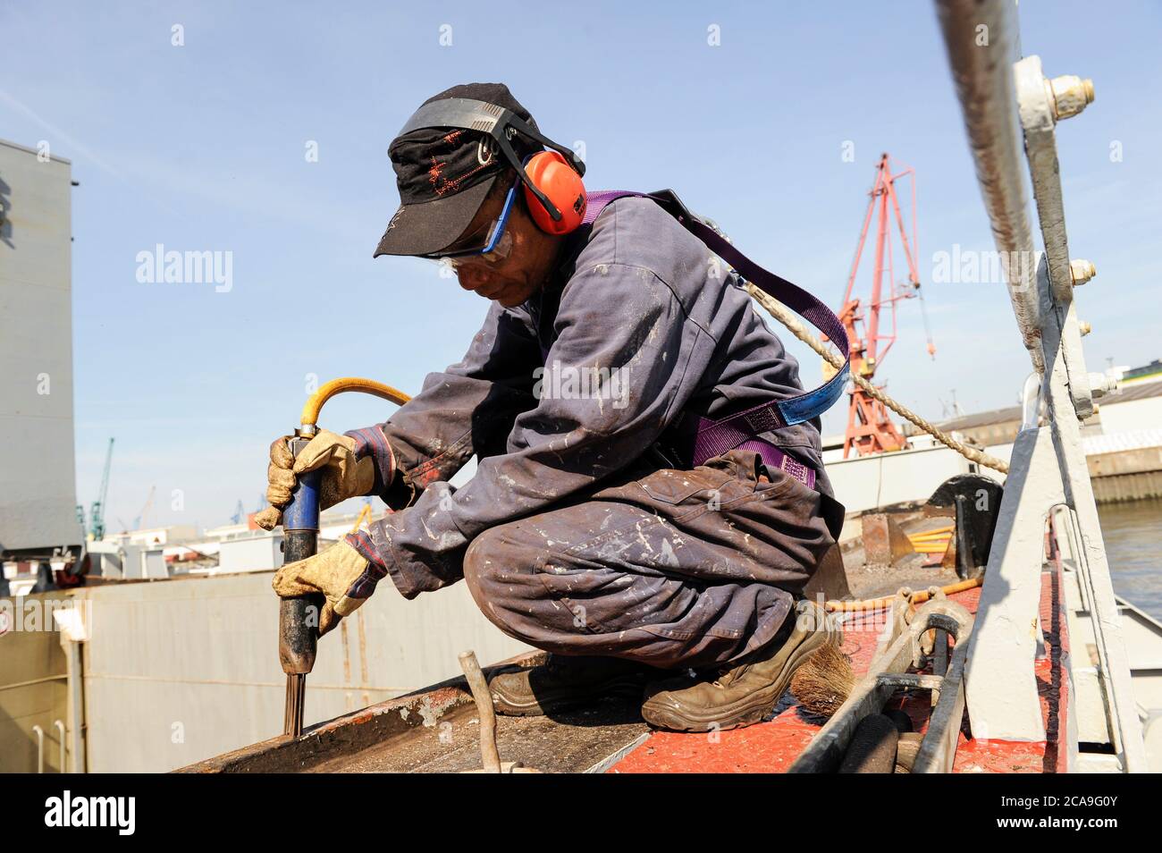 GERMANY, Hamburg, container ship at Hamurg port, Filipino seaman works on deck, corosion protection works with electric needle hammer / DEUTSCHLAND, Hamburg , MV Freya Container Feeder Schiff , Entrostungsarbeiten durch philipinnische Seeleute Stock Photo