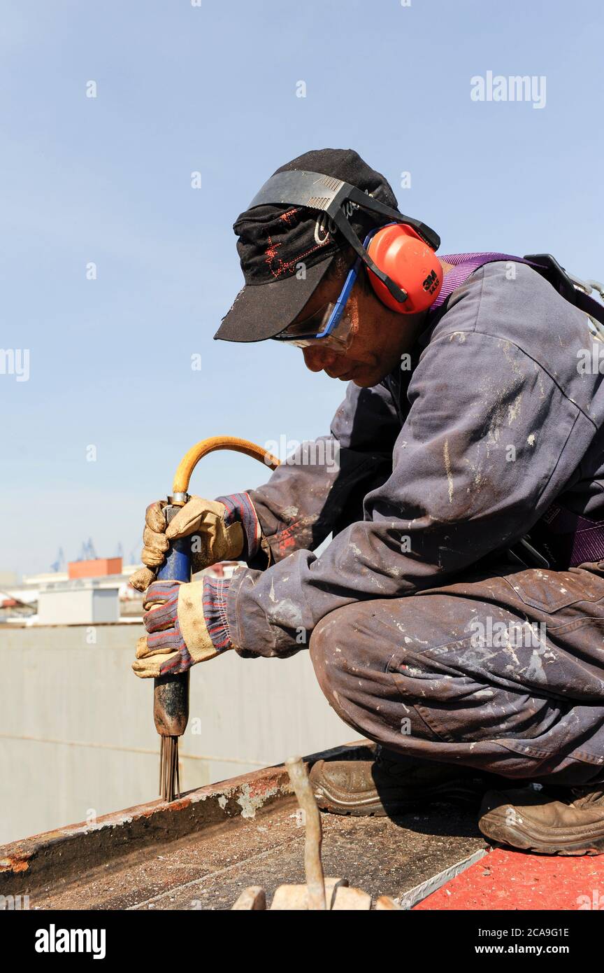 GERMANY, Hamburg, container ship at Hamurg port, Filipino seaman works on deck, corosion protection works with electric needle hammer / DEUTSCHLAND, Hamburg , MV Freya Container Feeder Schiff , Entrostungsarbeiten durch philipinnische Seeleute Stock Photo