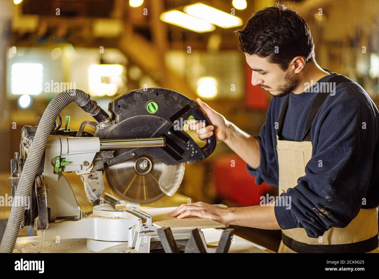 young caucasian hard working carpenter using circular saw