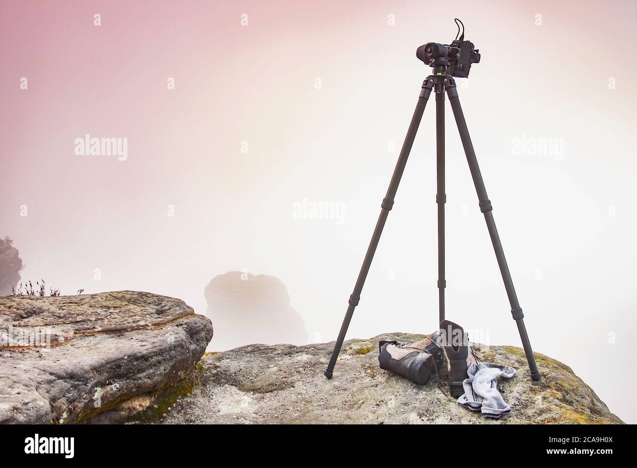 Camera on tripod against the misty background of the forest and ...
