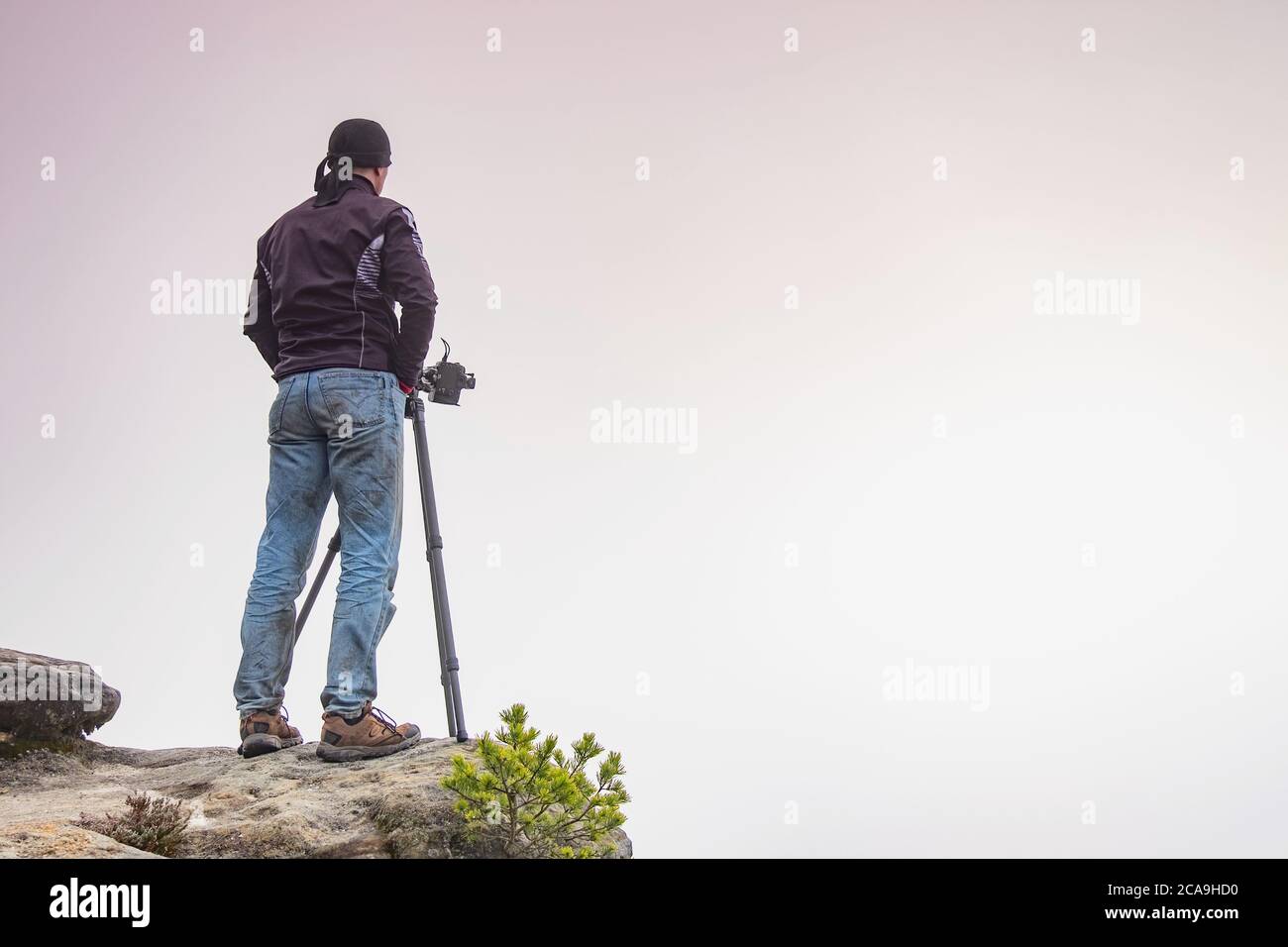 Silhouette of a professional photographer using a tripod, taking a photo of a mountain landscape Stock Photo