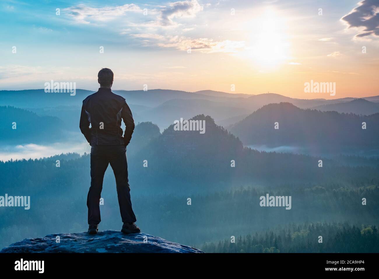 Hiker watching to autumn Sun at horizon . Beautiful moment. Spectacular mountain ranges silhouettes. Man reaching summit enjoying freedom Stock Photo