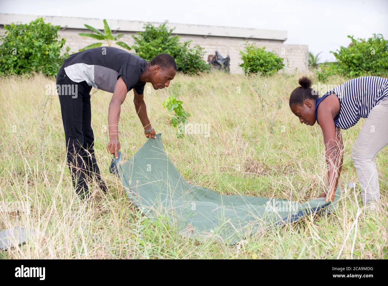 young african couple trying to spread a blanket in a park. Stock Photo