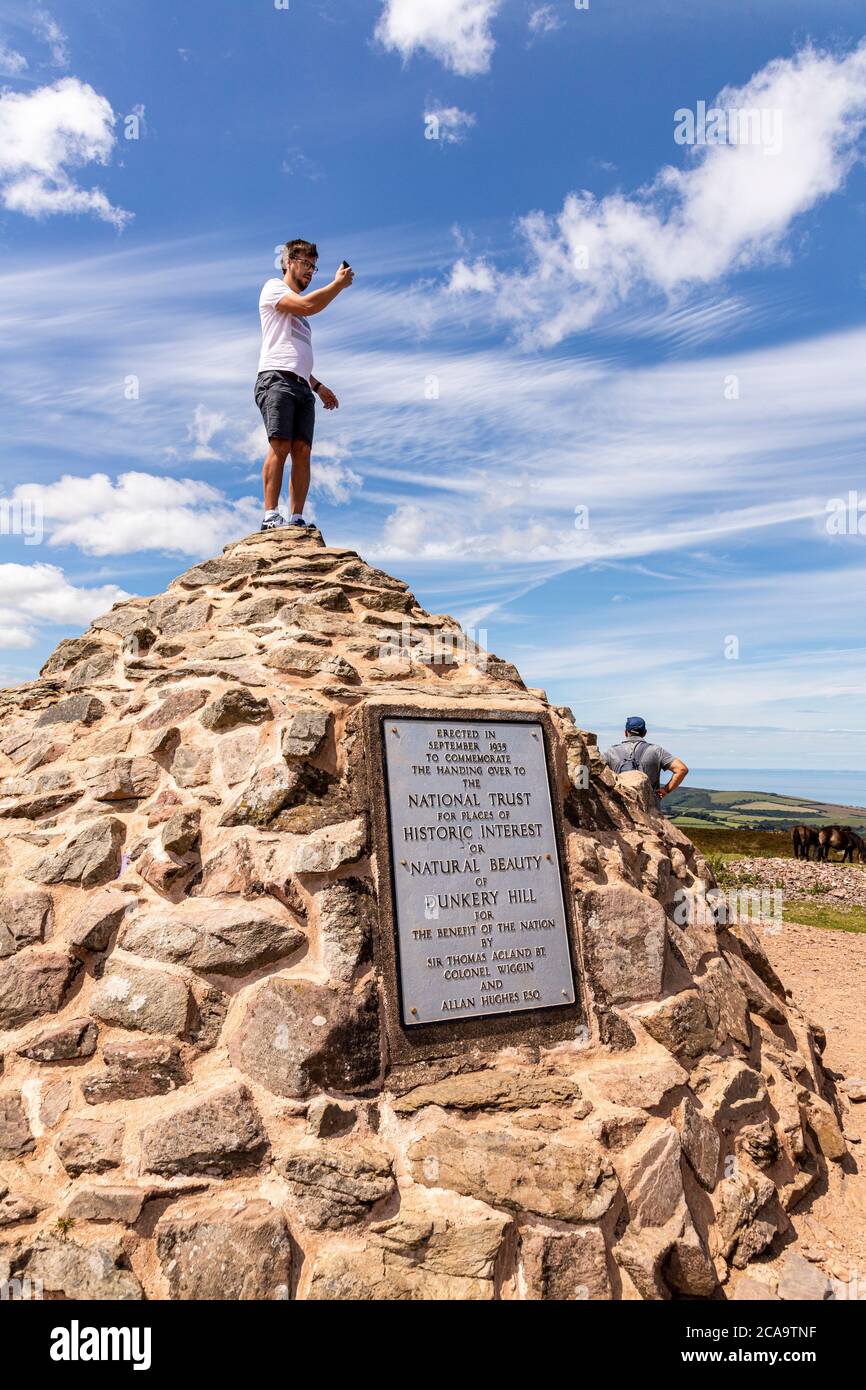 Exmoor National Park - A young man taking a selfie on top of the cairn marking the highest point on Exmoor, Dunkery Beacon, Somerset UK Stock Photo