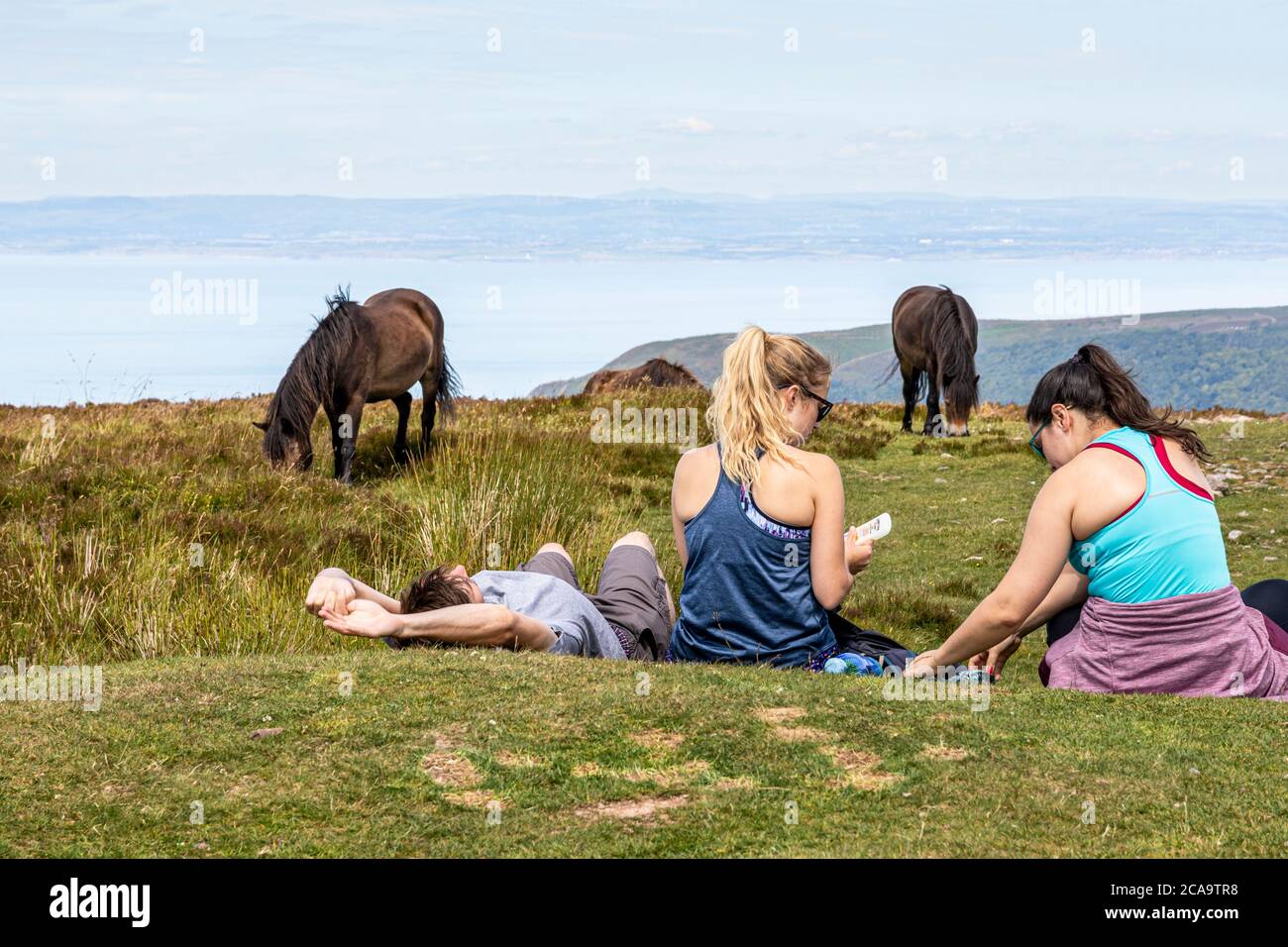 Exmoor National Park - Young people and ponies relaxing on the highest point of Exmoor, Dunkery Beacon 1705 feet 520 metres, Somerset UK Stock Photo