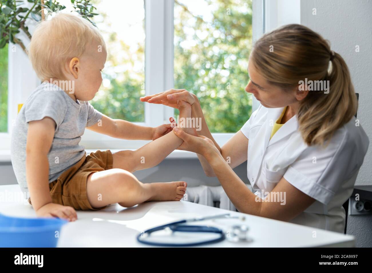 female orthopedist examining little child foot condition in clinic Stock Photo