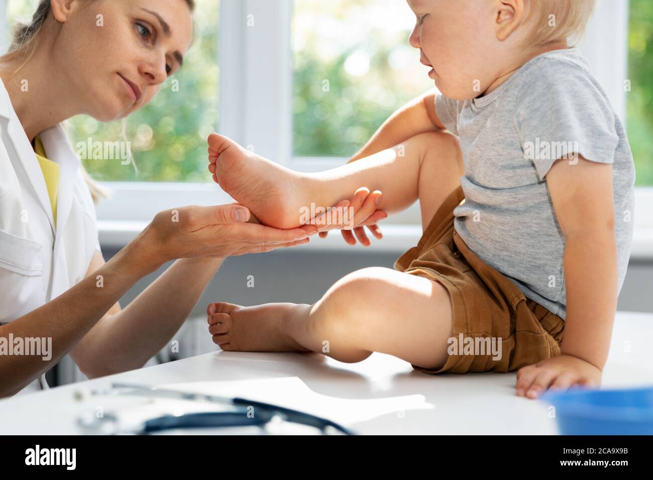 orthopedist podiatrist checking child patient feet condition in clinic office Stock Photo