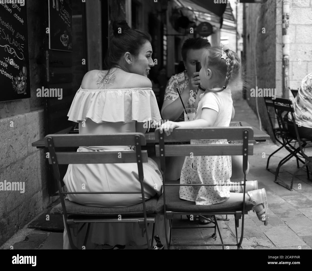 Montenegro, Sep 22, 2019: Couple with daughter spending time at a street café in Kotor Old Town (B/W) Stock Photo