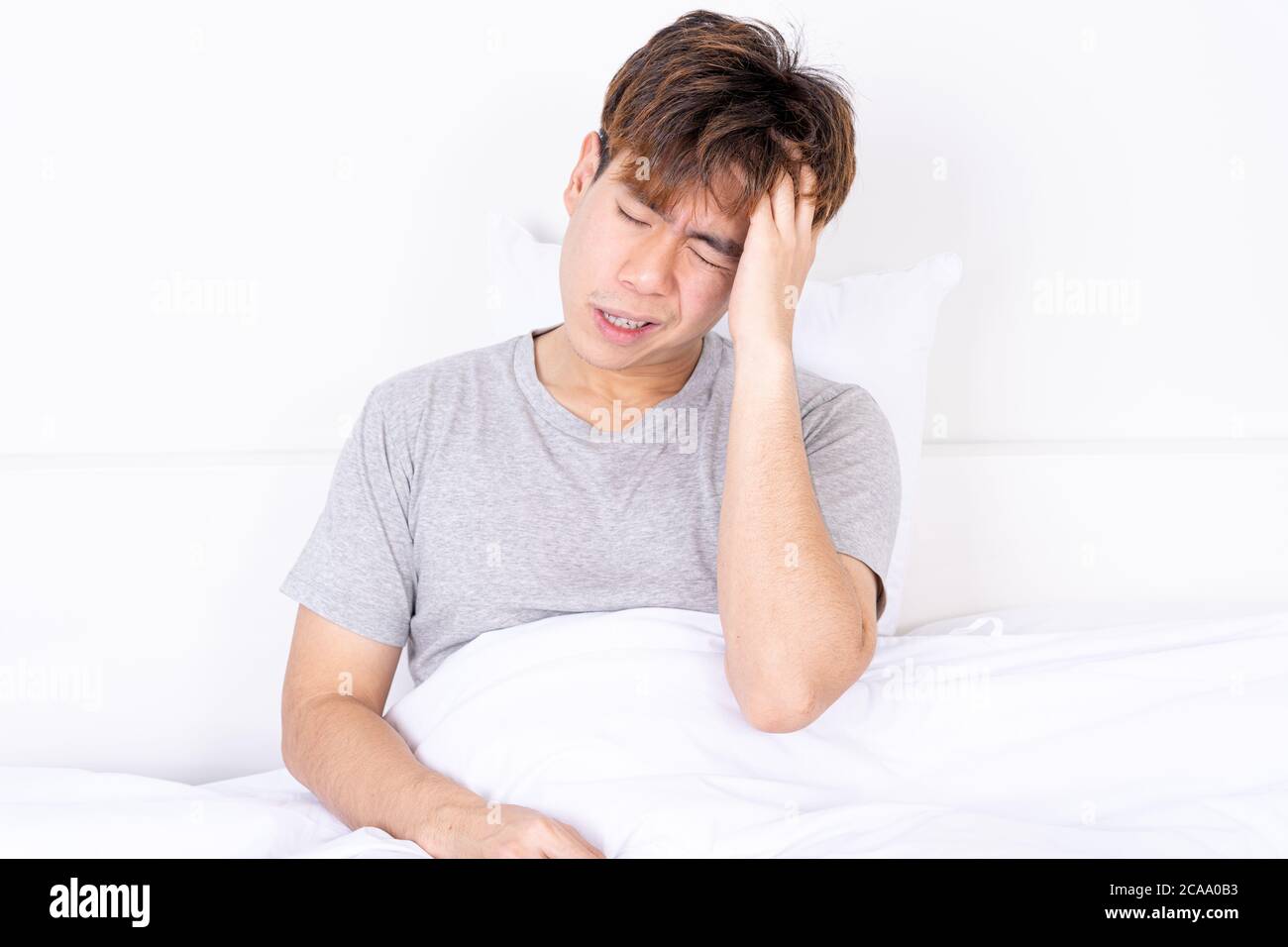 Young man suffering from headaches after wake up on the bed. Healthcare medical or daily life