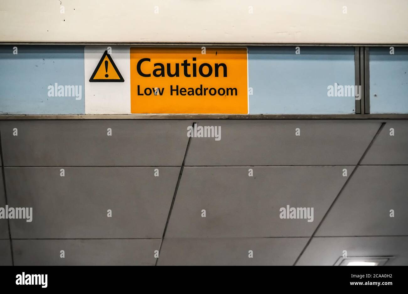 Orange ' Caution low headroom ' sign on roof above elevators Stock Photo