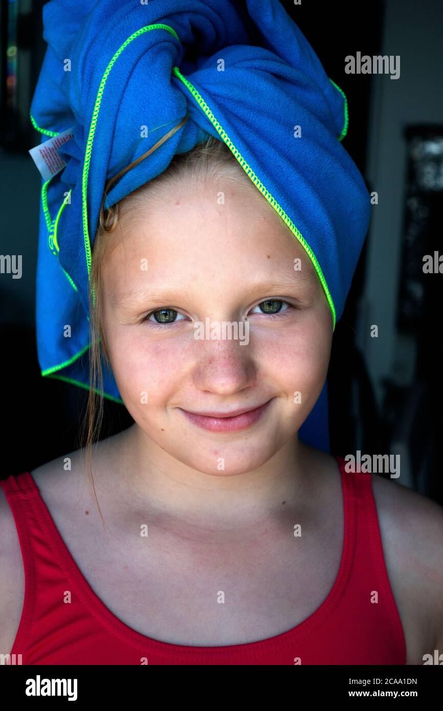 Polish preteen girl with a blue towel wrapped around wet hair smiling