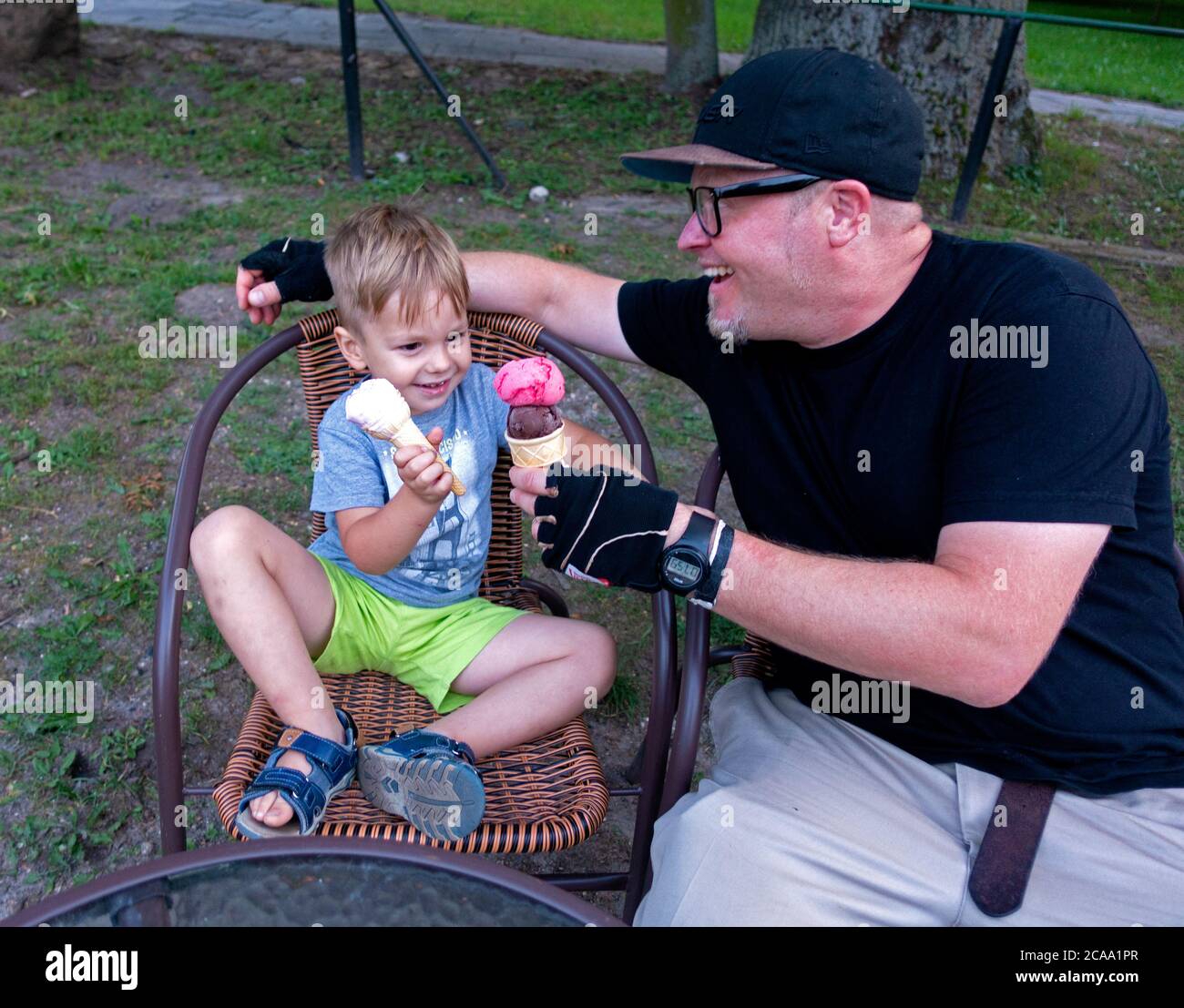 Father and son toasting ice cream cones together in an outdoor patio. Rzeczyca Central Poland Europe Stock Photo
