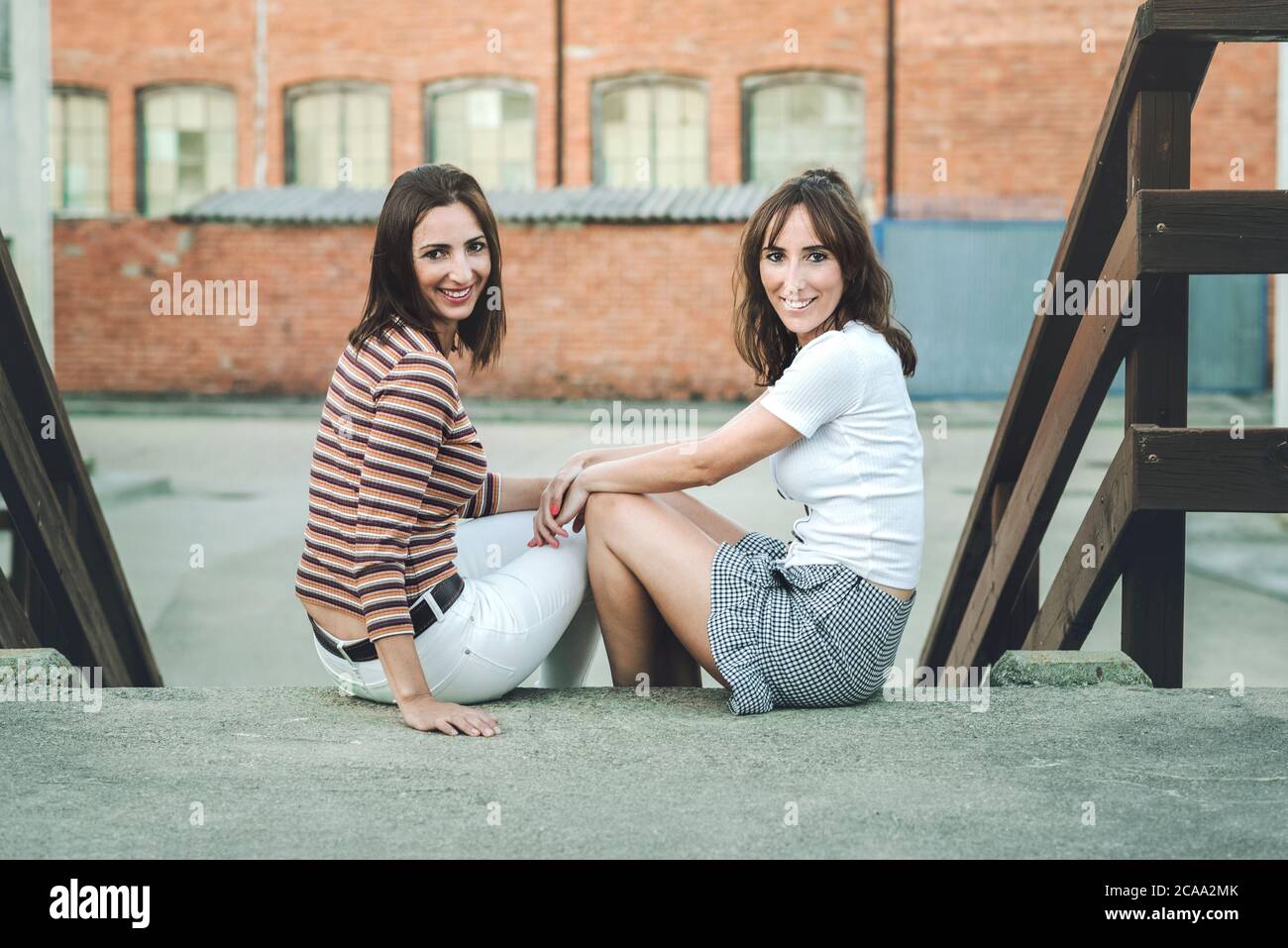 Two happy young women sitting hi-res stock photography and images - Alamy
