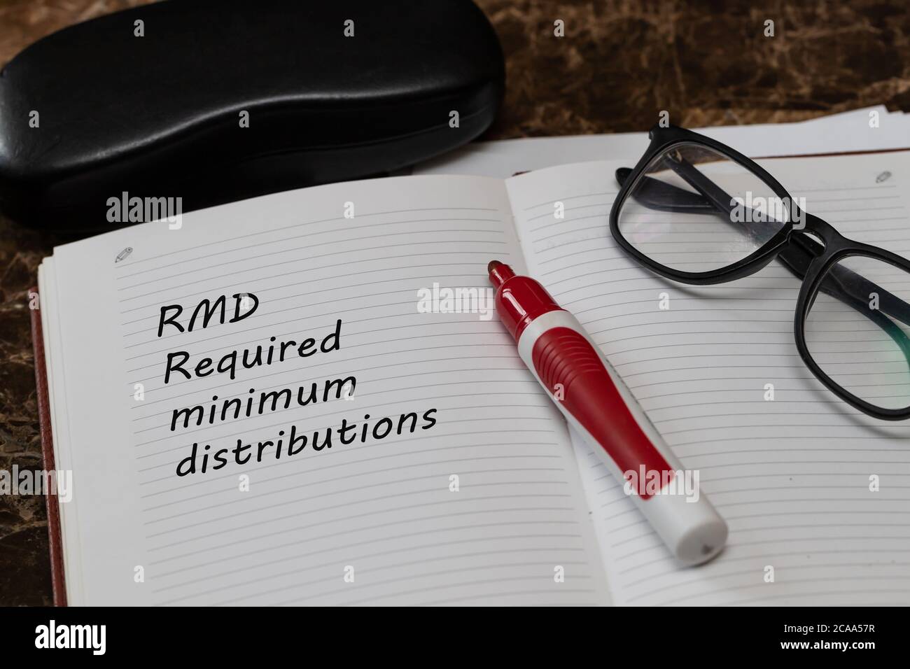 Desktop office desk, notepad, glasses, pen and notes with RMD require minimal distribution on the heading Stock Photo
